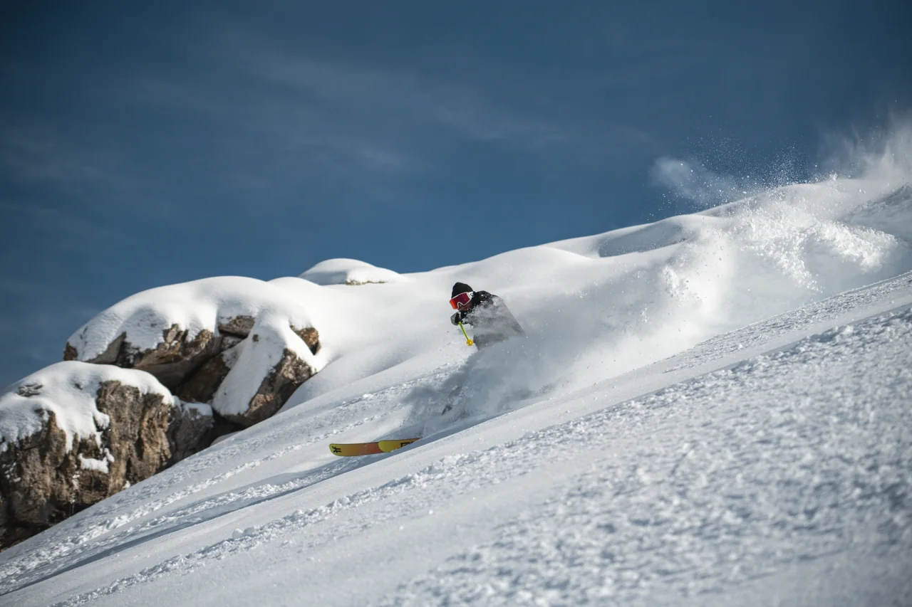Uno sciatore scende nella neve fresca fra pendii e rocce