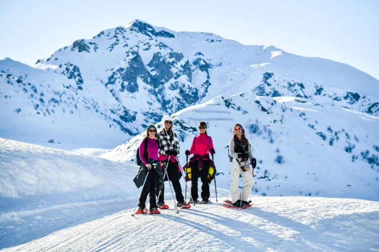 Escursionisti con le ciaspole sulla neve, davanti alle cime delle Alpi