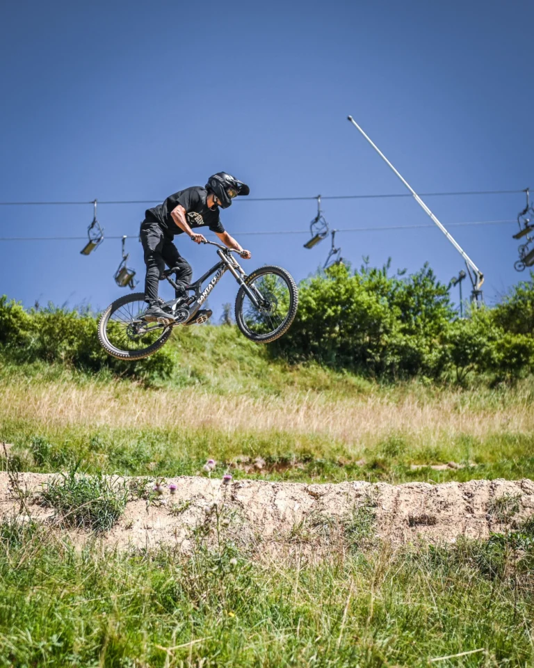 Un rider in salto nel Bikepark, con la seggiovia sullo sfondo