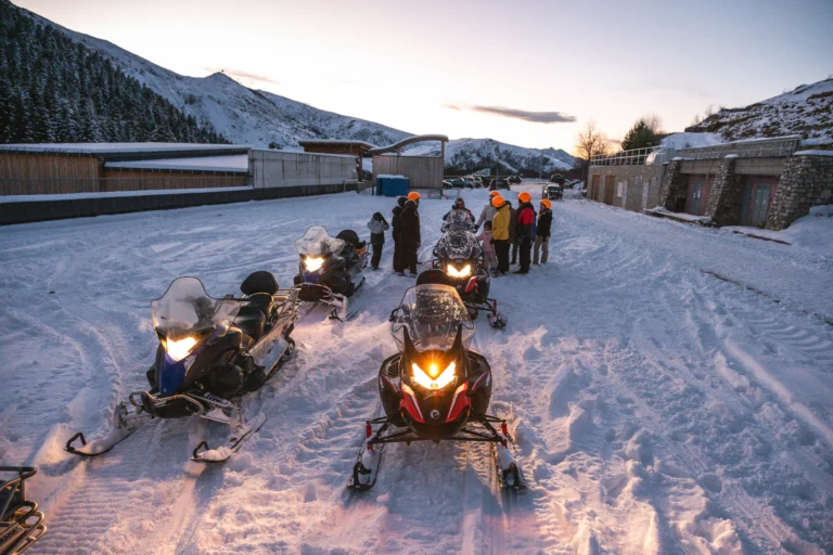 Motoslitte con fari accesi in primo piano e gruppo dietro