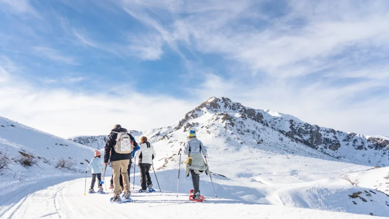 Escursionisti con ciaspole nel paesaggio innevato e soleggiato.