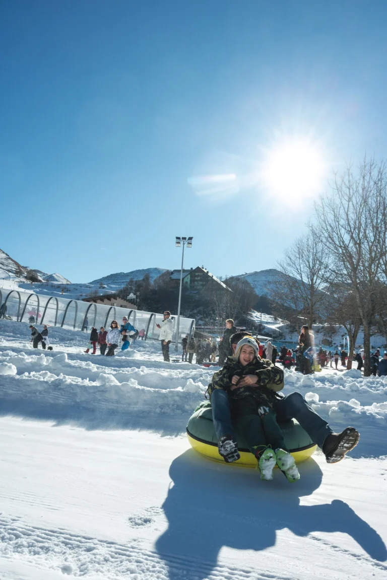 Un adulto e un bambino scendono sulla neve su una ciambella gialla