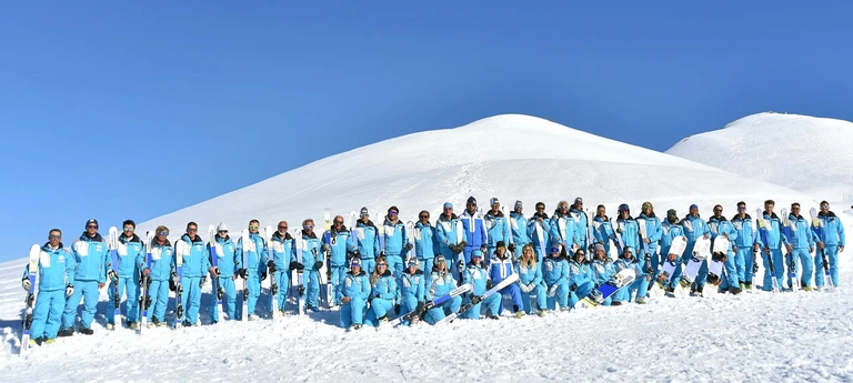I maestri della Scuola Sci Prato Nevoso in divisa azzurra, schierati sulla neve sotto il cielo blu