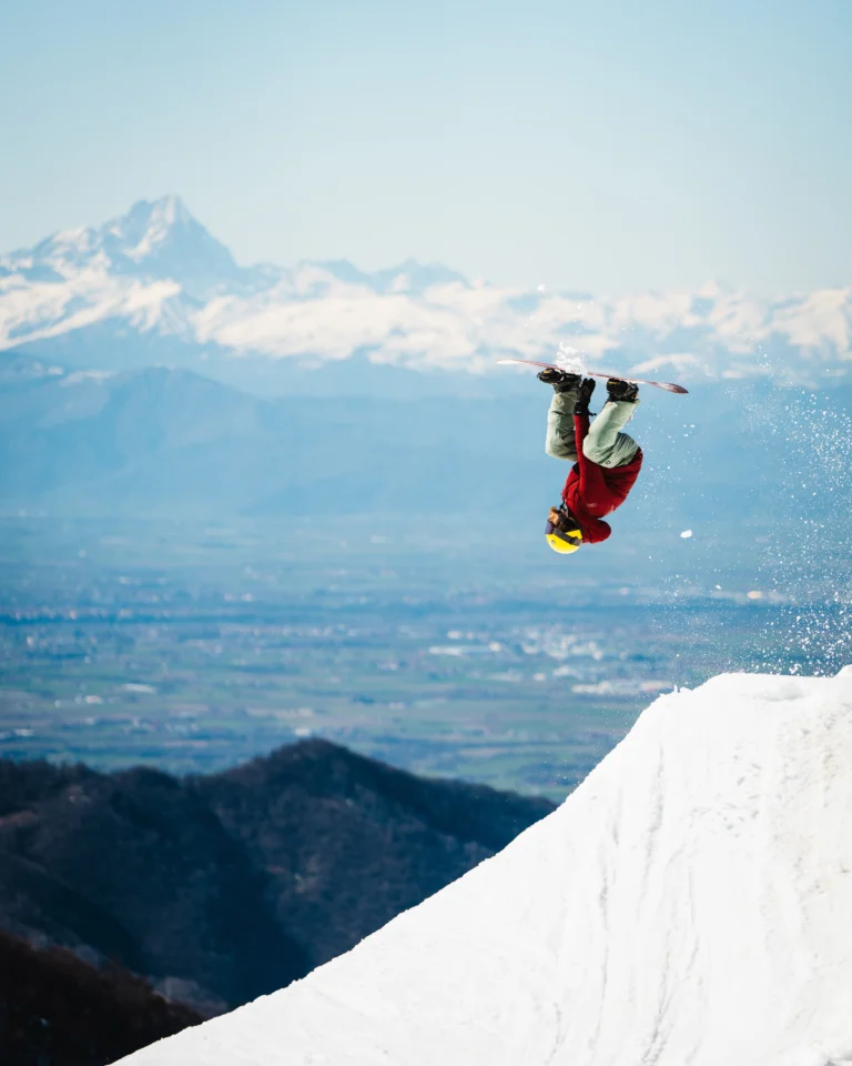Snowboarder in rotazione sopra salto e valle