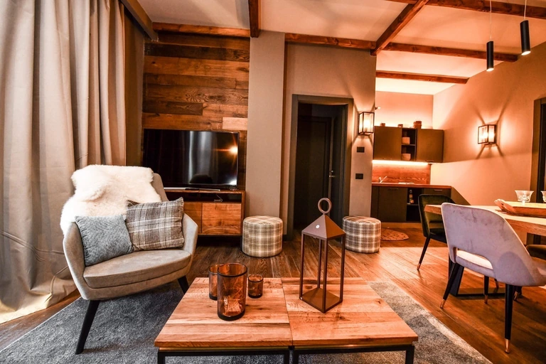 Un soggiorno di Chalet Everest con poltrona, tavolino in legno e cucina sullo sfondo