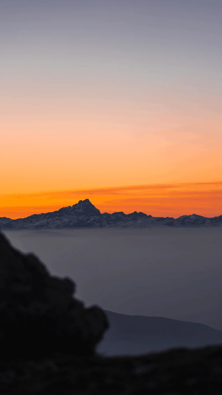 Il profilo delle montagne sotto un cielo arancione al tramonto