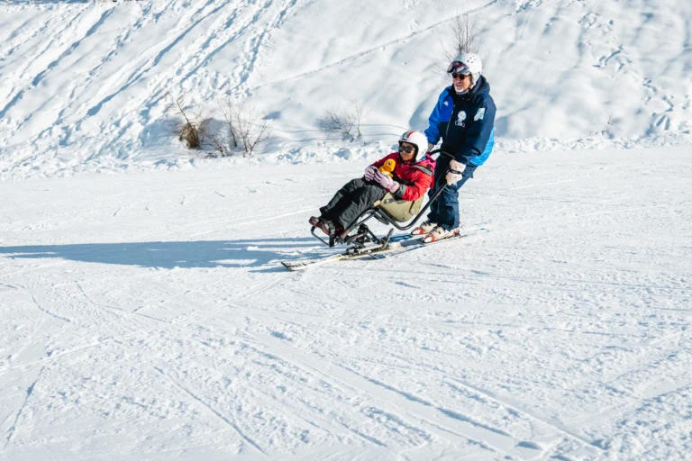 Persone sulla neve durante un’attività di sci adattato.