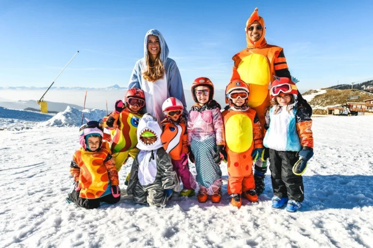 Bambini in costume con gli animatori travestiti, sulla neve sotto il cielo blu