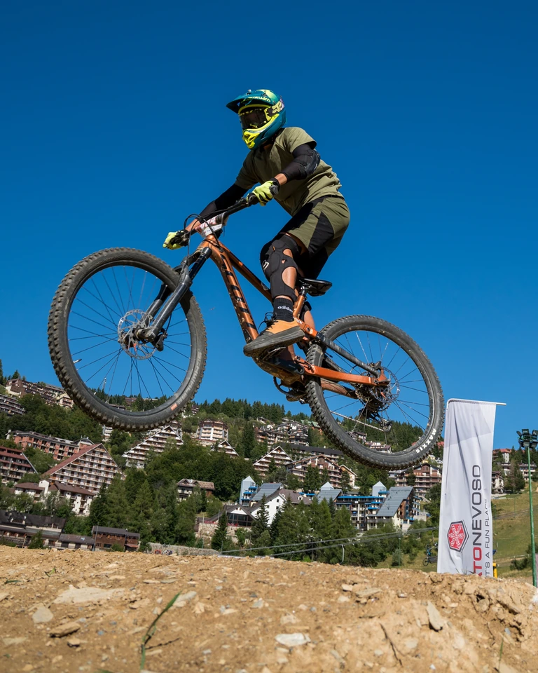 Rider MTB in salto, con casco verde, sulle piste del Bikepark di Prato Nevoso