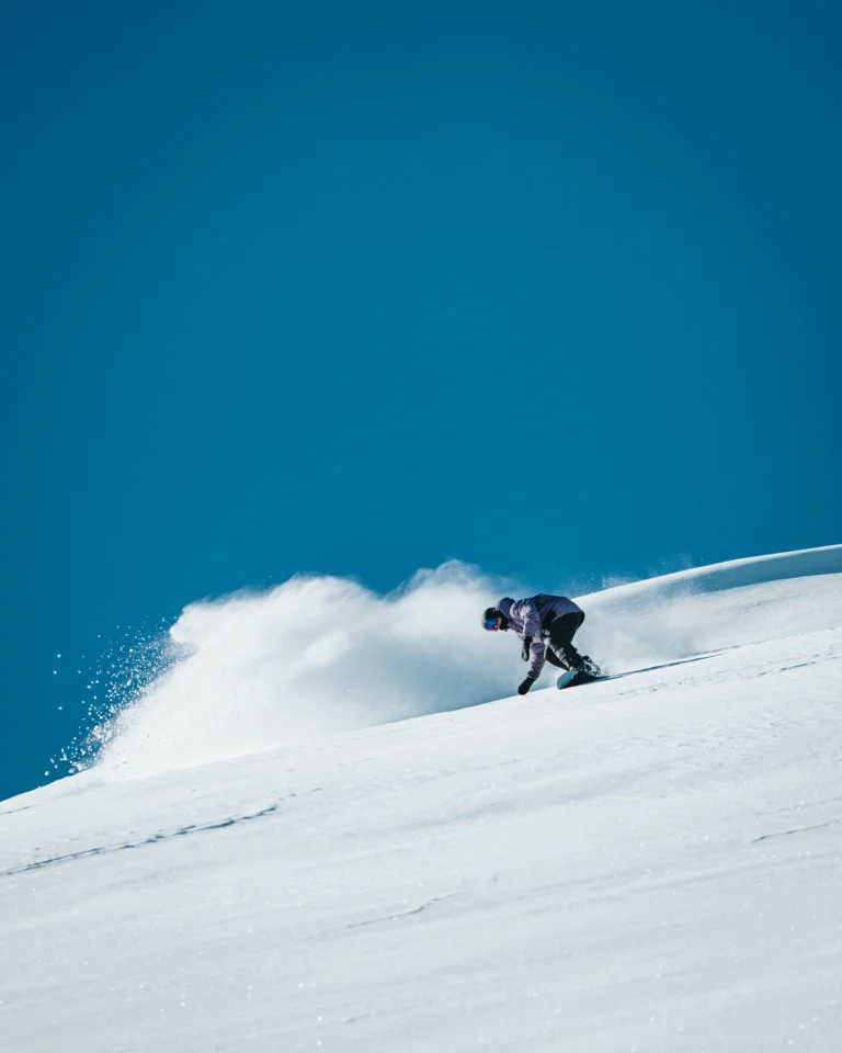 Sciatore solleva nuvola di neve fresca sul pendio bianco.
