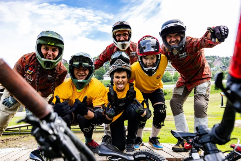 Giovani rider e maestri della Mondolé MTB School sorridono insieme, con caschi e protezioni