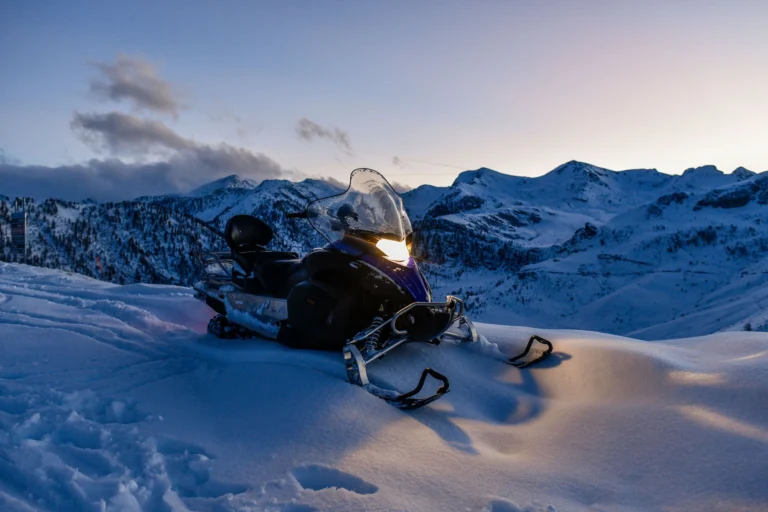 La motoslitta accende il faro mentre la luce lascia il paesaggio innevato