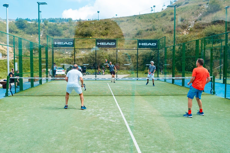 Quattro giocatori durante una partita sul campo da padel di Stalle Lunghe, con il pendio sullo sfondo