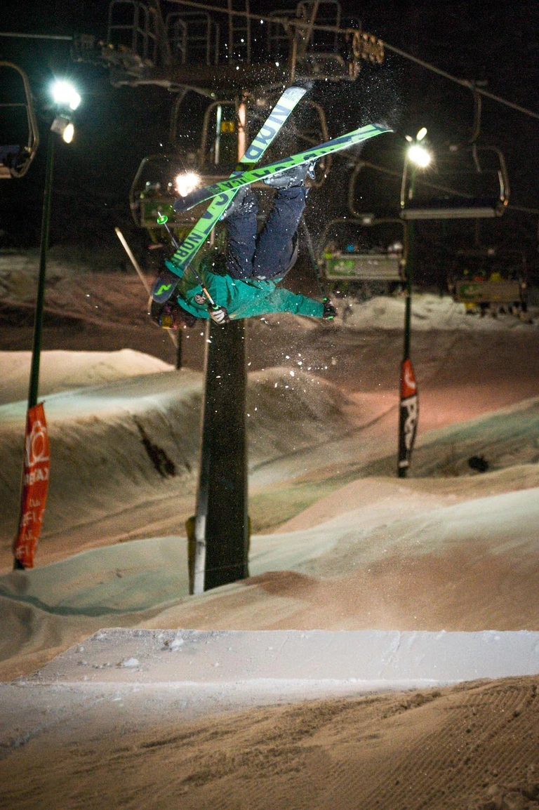 Un freeskier in salto rovesciato sotto le luci dello Snowpark