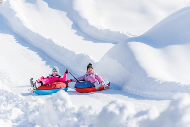 Bambini sui gommoni colorati lungo la pista di snowtubing.
