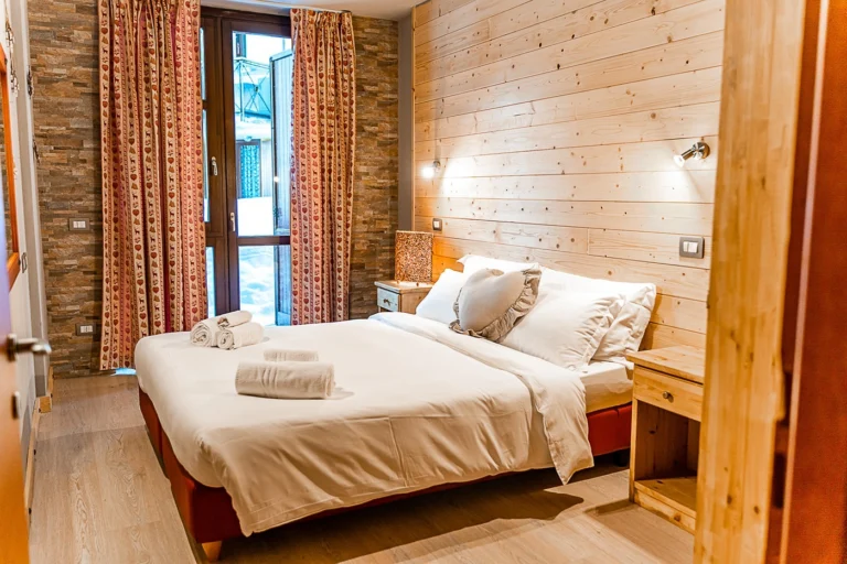 Una camera del Residence Stalle Lunghe, con rivestimenti chiari in legno