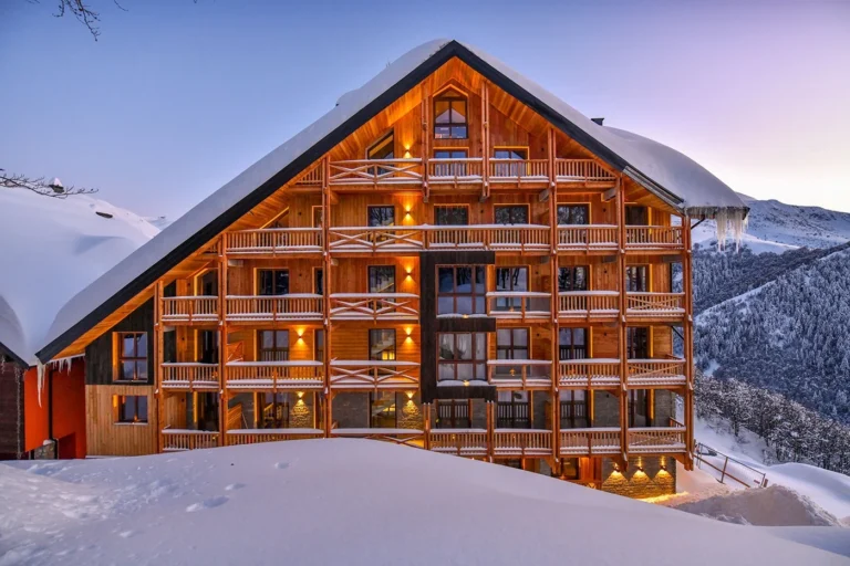 La facciata in legno del Chalet Everest, con la neve e le luci accese