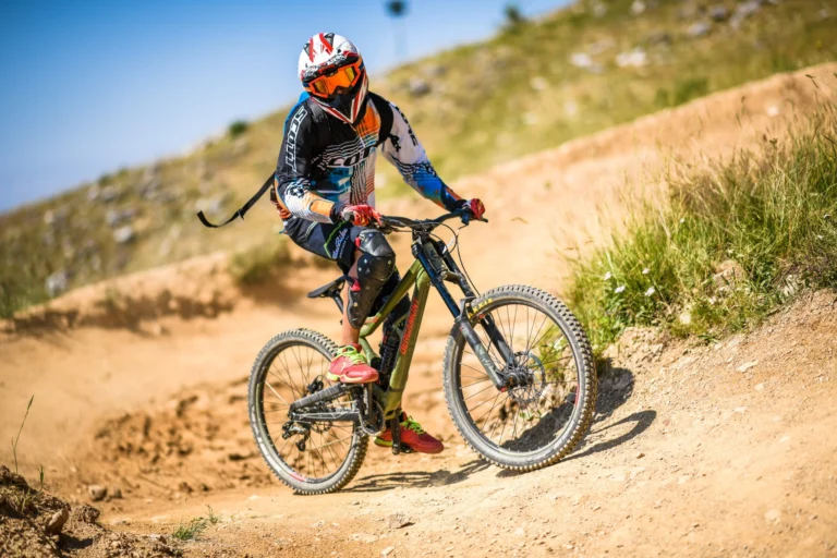 Un rider con casco integrale affronta una curva sterrata con una bici downhill
