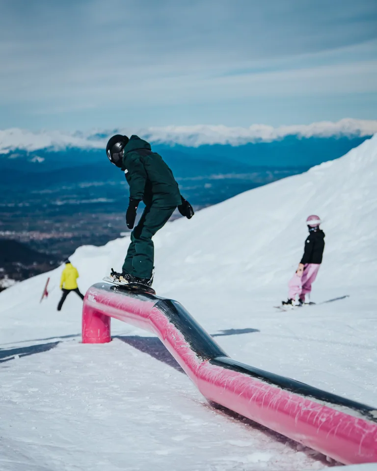 Snowboarder percorre un rail rosa nello Snowpark