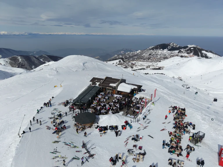 Vista aerea dello Chalet Il Rosso con ospiti sulla terrazza e tavoli sulla neve, tra le piste di Prato Nevoso.