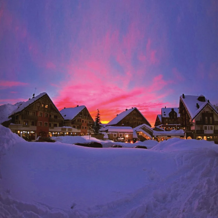 Gli chalet di Stalle Lunghe nella neve, sotto un cielo rosa al tramonto