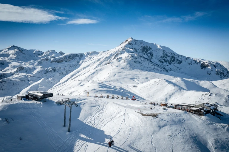 Vista dall’alto dell’arrivo della telecabina La Rossa e dello Chalet Il Rosso sulla neve, con il Mondolè sullo sfondo