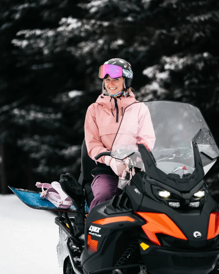 Donna sorridente con casco rosa seduta sulla motoslitta