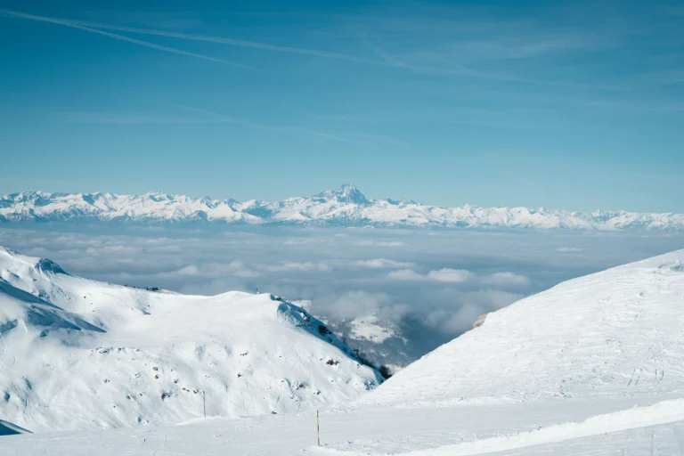Panorama molto ampio di neve e catena montuosa lontana sotto cielo azzurro.