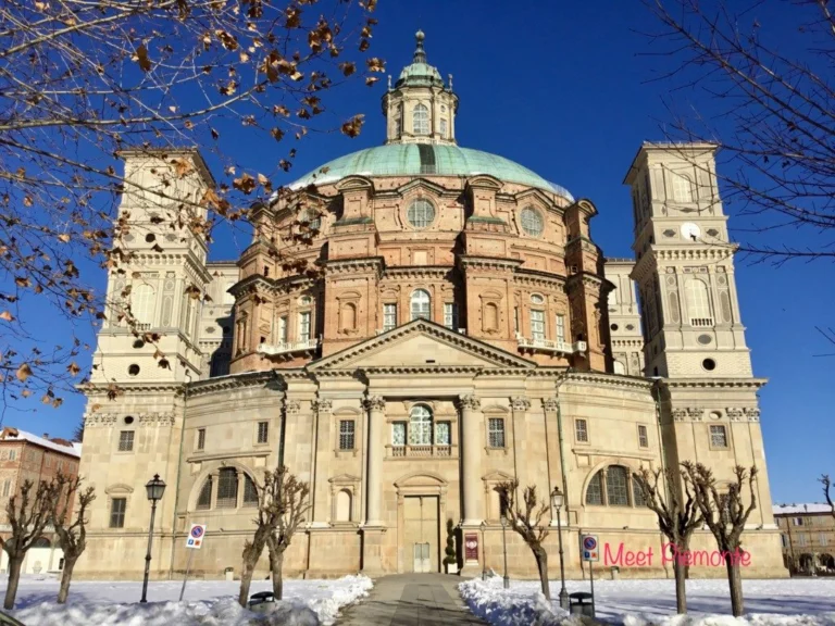 La facciata e la cupola del Santuario di Vicoforte sotto un cielo blu, con la neve ai piedi