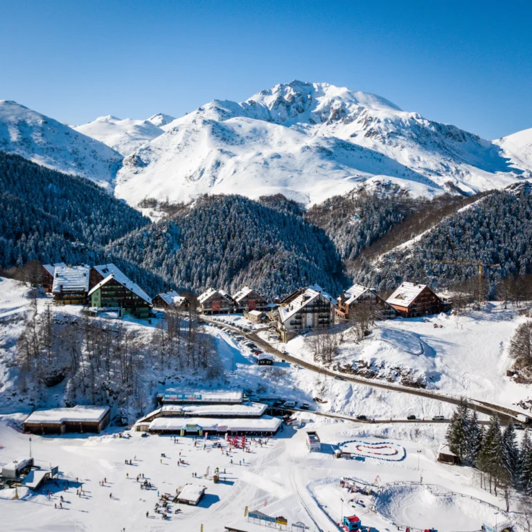 Vista aerea del campo scuola nella Conca di Prato Nevoso, con il paese e le montagne innevate sullo sfondo.