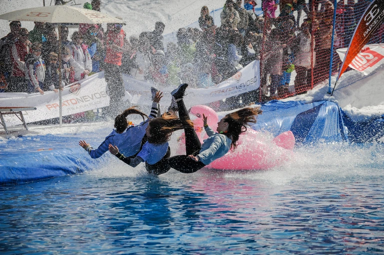 Partecipanti con un gonfiabile rosa entrano nella piscina tra gli spruzzi durante lo Spring Splash 2018