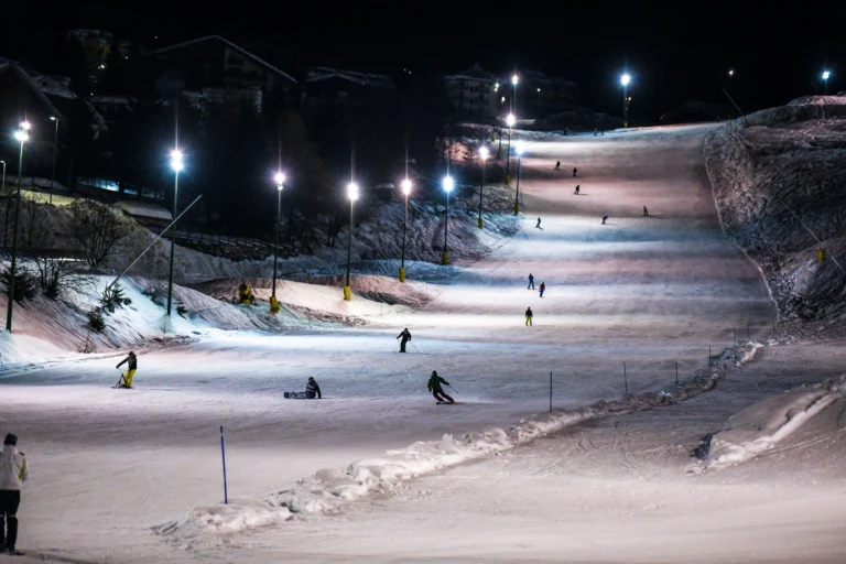 Sciatori sulle piste illuminate della Conca di Prato Nevoso durante lo sci notturno.