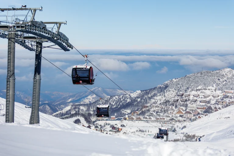 Telecabina La Rossa sopra le piste innevate con il panorama delle montagne.