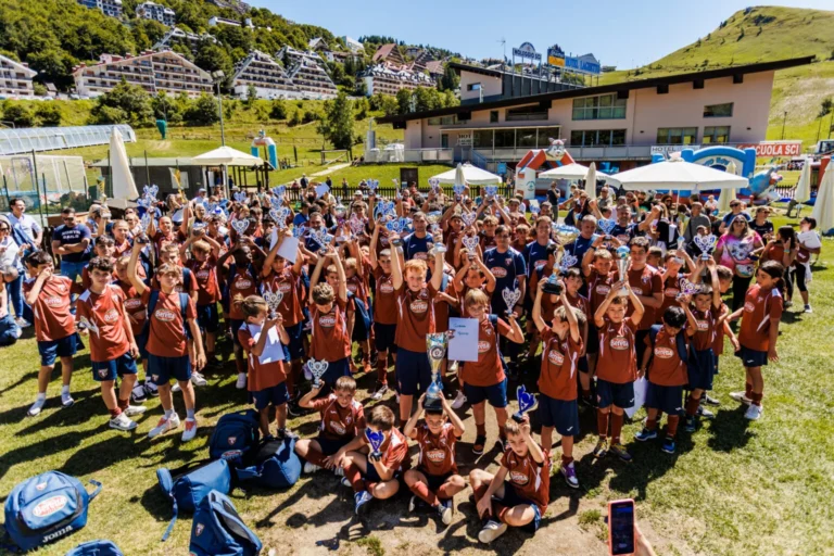 Un grande gruppo di partecipanti al camp di calcio, riunito sul prato con lo staff