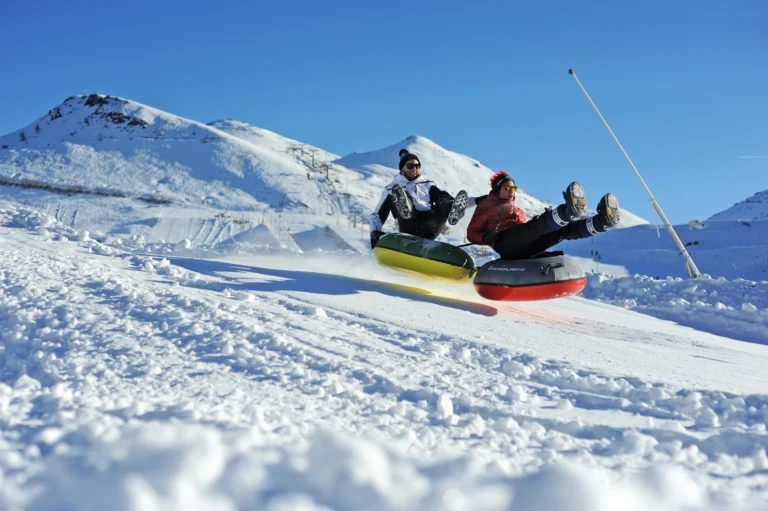 Due persone scendono sulle ciambelle dello Snowtubing tra le montagne innevate di Prato Nevoso.
