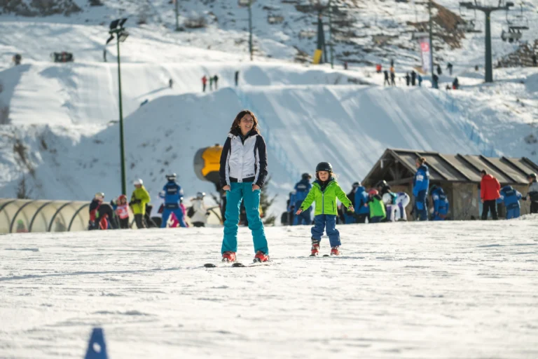 Maestra di sci e bambini sul campo scuola innevato.