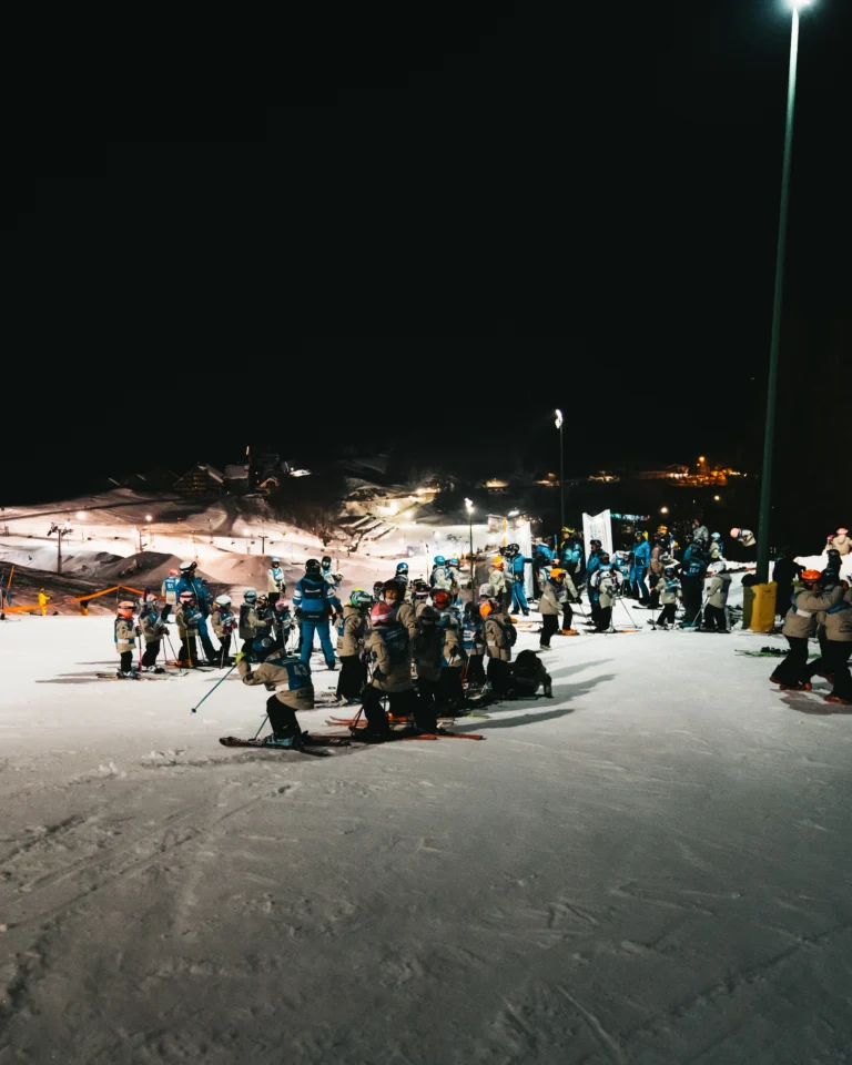 Gruppo di giovani sciatori con i maestri sulle piste illuminate di Prato Nevoso.